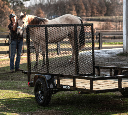 A Carry-On trailer in a field with a horse and horse handler in the background