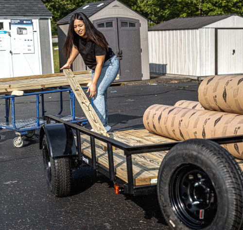 Woman loading lumber into a trailer
